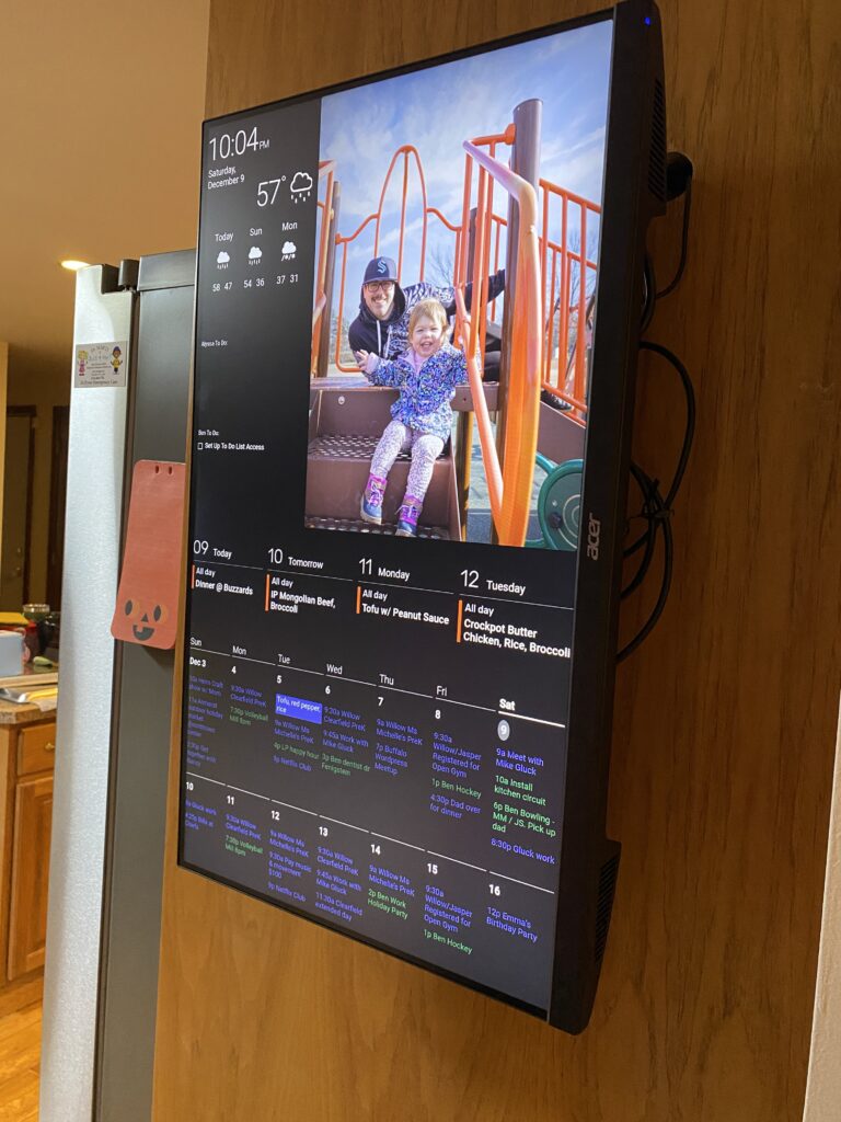 digital display board showing family photos and calendar in kitchen